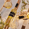 Lorenz Chardonnay Biowein wird zum Genuss mit Käse ins Glas eingeschenkt vor weißen Holzweinkisten