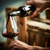 Urschrei Biowein wird ins Glas zum Dekantieren eingeschenkt vor Holzweinkisten